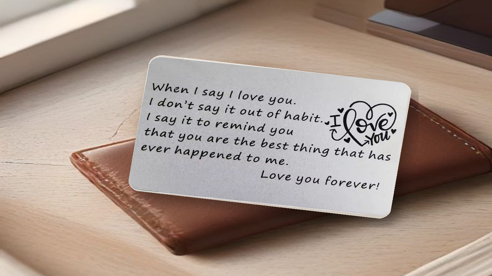 Love You Forever metal wallet card resting in front of a brown leather wallet